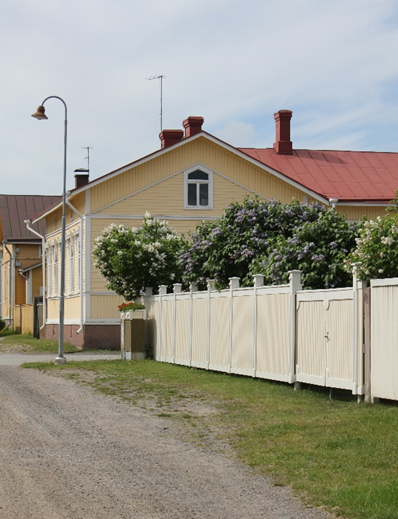 Katunäkymä Porin 6. osan, kuukkarin kadulta. Vasemmalla etuallalla hiekkatie, oikealla etualalla keltainen aita ja keskellä takana keltainen puutalo, jossa punainen katto.