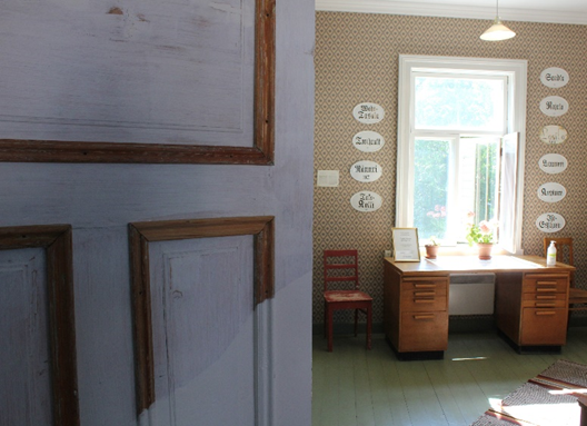 kuvassa vasemmalla, etualalla on ovi, jota osittain maalattu. kuvan oikealla, takana on ikkuna, jonka ympärillä nimikylttejä