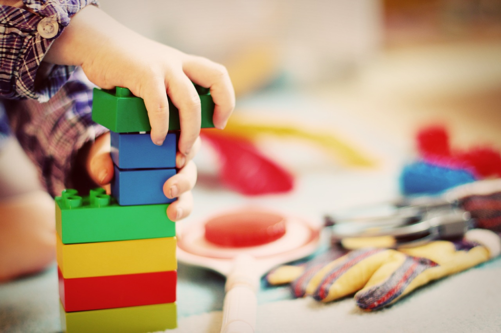 Lapsi rakentaa värikkäistä palikoista tornia.